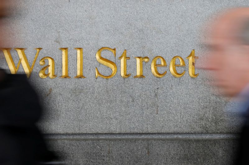 People walk by a Wall Street sign close to the