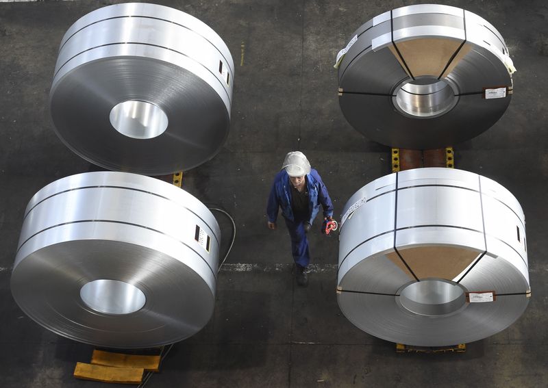 An employee passes some steel rolls at the plant of