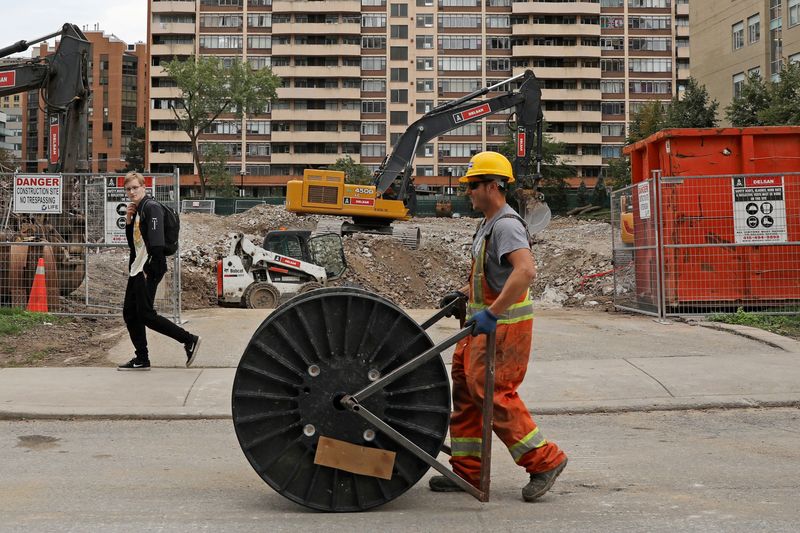 A construction worker passes a condominium site with a roll