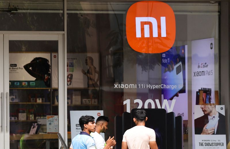 People walk past Xiaomi, a Chinese manufacturer of consumer electronics,
