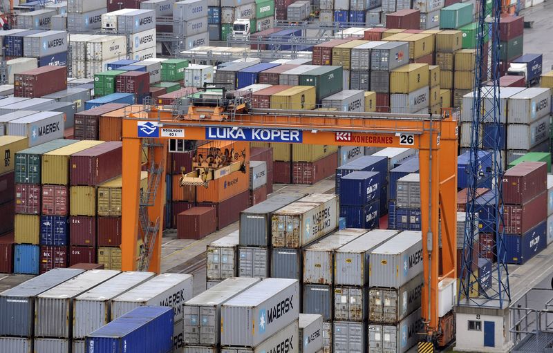 A crane is pictured next to lined up containers at