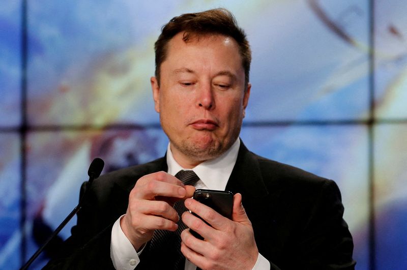FILE PHOTO: Elon Musk looks at his mobile phone during