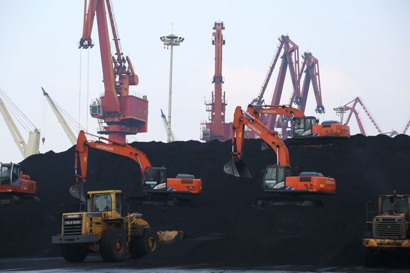 Workers operate loaders unloading imported coal at a port in