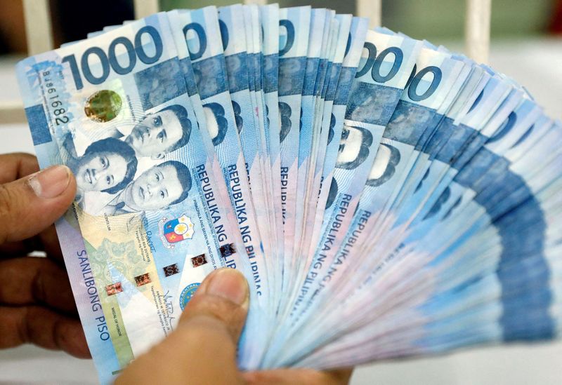 FILE PHOTO: A worker shows Philippine peso bills inside a