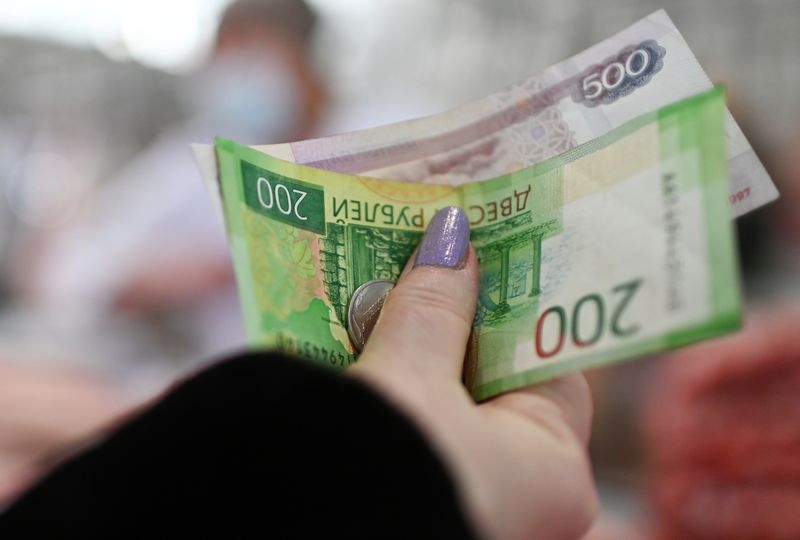 A customer hands over Russian rouble banknotes and coins to