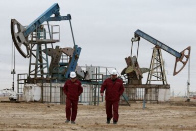 FILE PHOTO: Workers walk as oil pumps are seen in