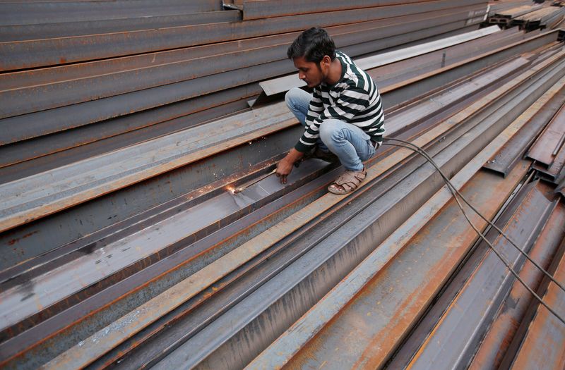 FILE PHOTO: A worker cuts iron rods outside a workshop