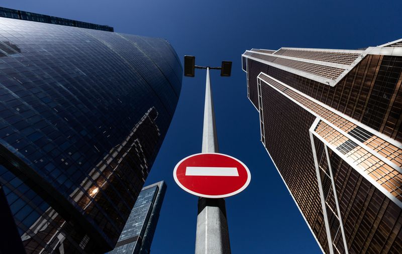 A stop road sign is seen next to skyscrapers at