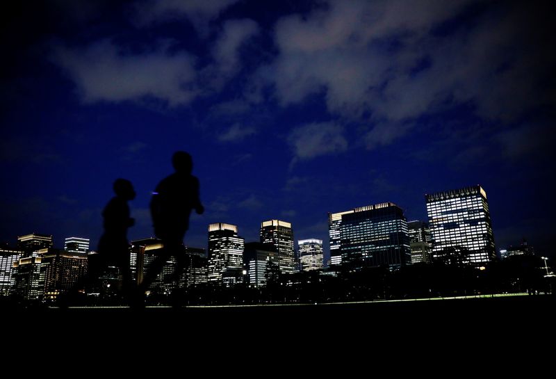People run with Tokyo’s business district in background, in Tokyo