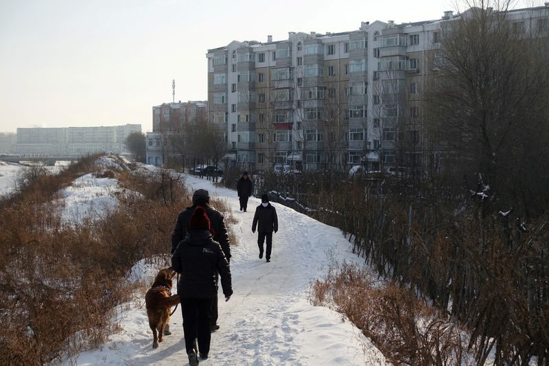 People walk next to residential buildings in the coal city