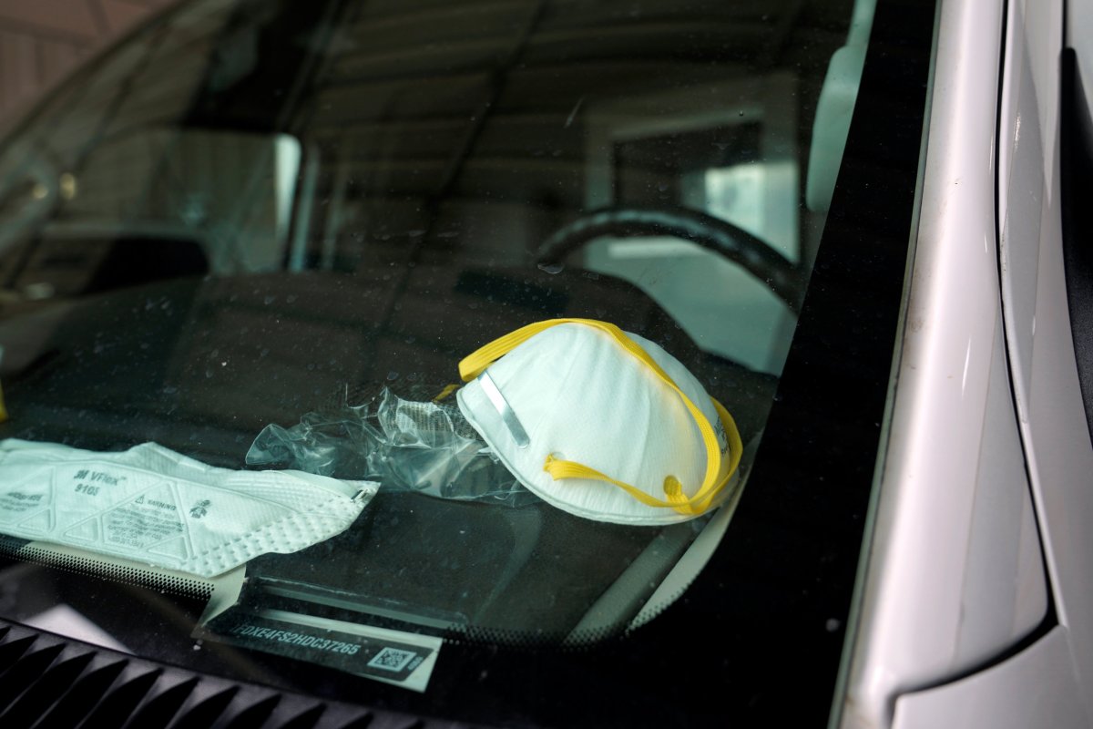 A protective face mask is seen on the dashboard of