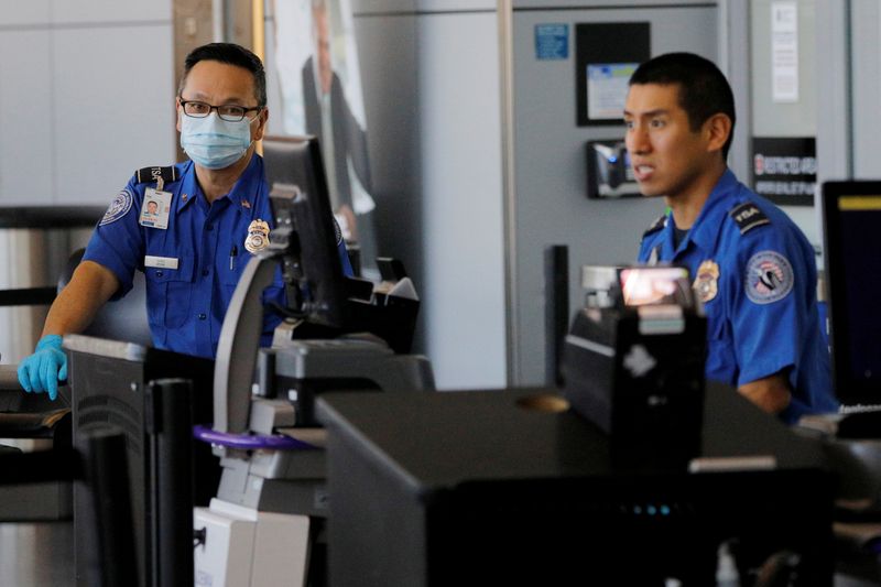 A TSA officer wears a mask and gloves at Logan