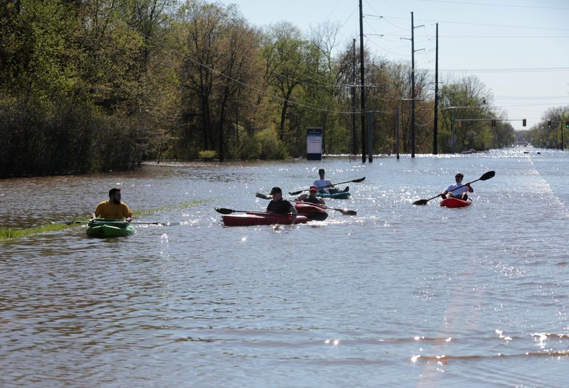 Residents paddle kayaks along a flooded street along the Tittabawassee