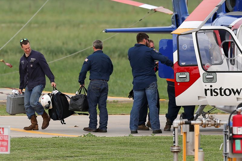 Workers disembark from a helicopter after being evacuated from oil
