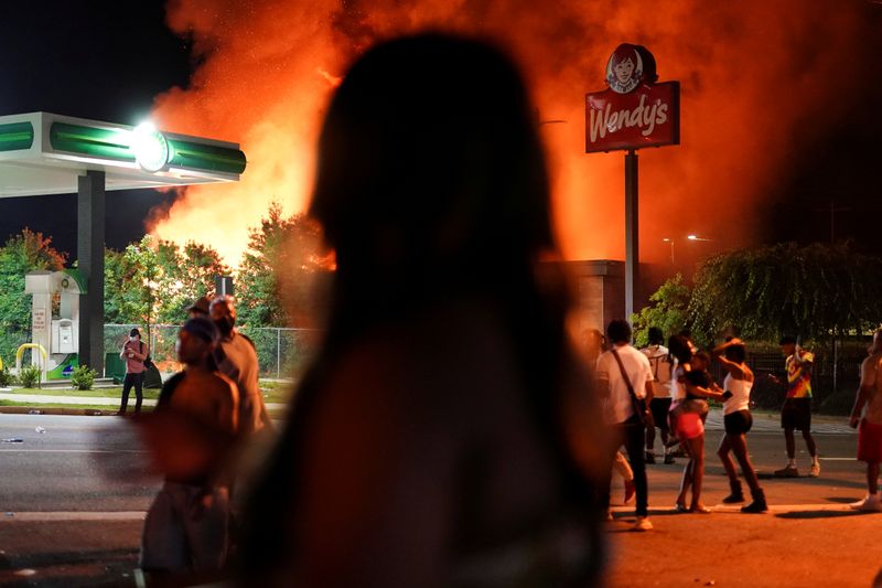 People watch as a Wendy’s burns following a rally against