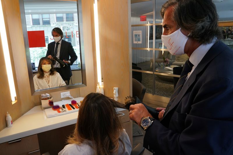 Julien Farel cuts a woman’s hair in his salon, on