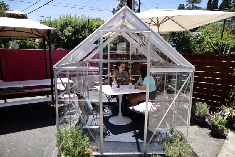 People eat lunch in a social distancing greenhouse dining pod