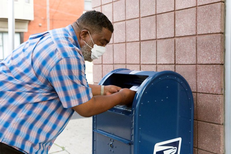 FILE PHOTO: An individual deposits letters into a U.S. Postal