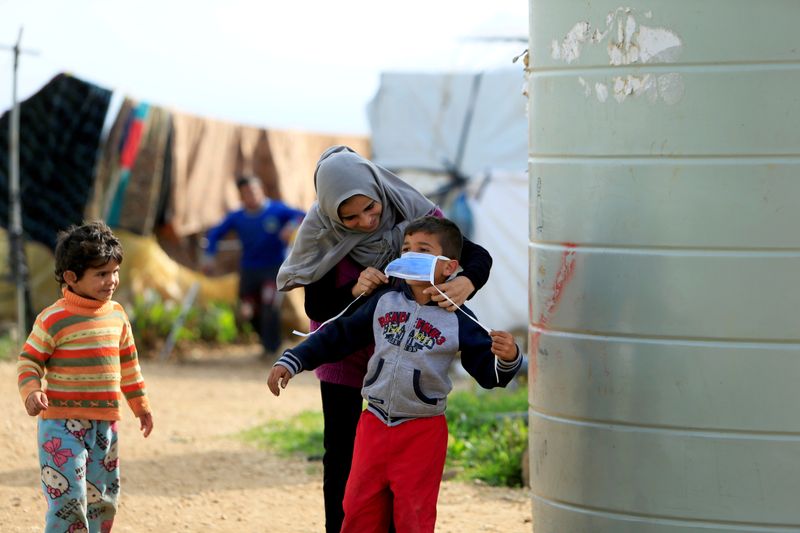 FILE PHOTO: A Syrian refugee woman puts a face mask