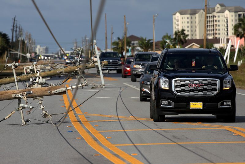 Cars drive around downed power lines after Hurricane Sally in