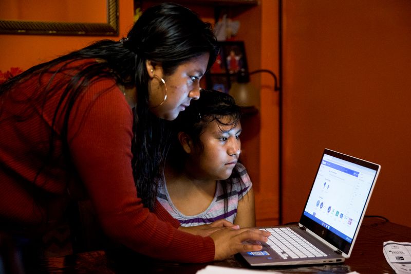 Belen Cruz helps her daughter to sign in online as
