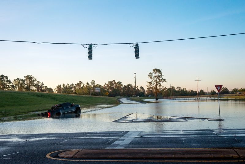 A submerged car is pictured on a flooded street after