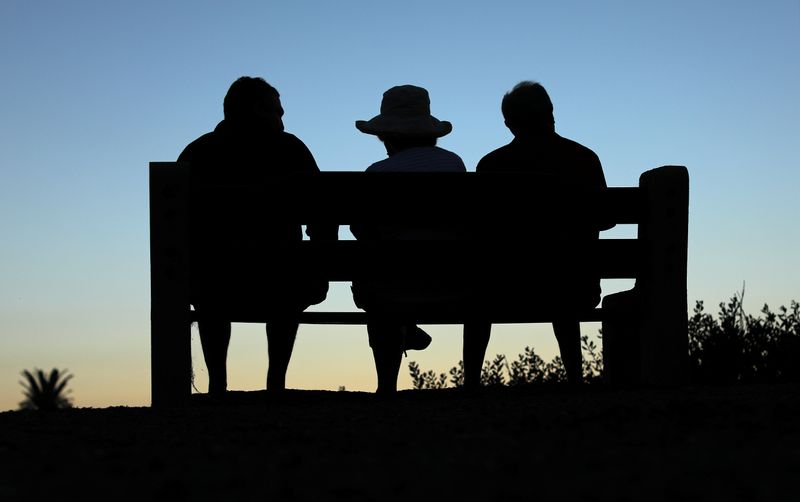 FILE PHOTO: Elderly people sit on a park bench after