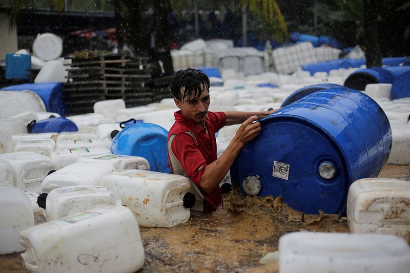 A man recovers plastic barrels from a business affected by