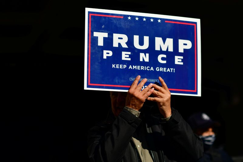 A Trump supporter clutches a campaign sign with both hands