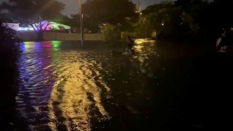 People walk in floodwaters caused by Storm Eta in Fort