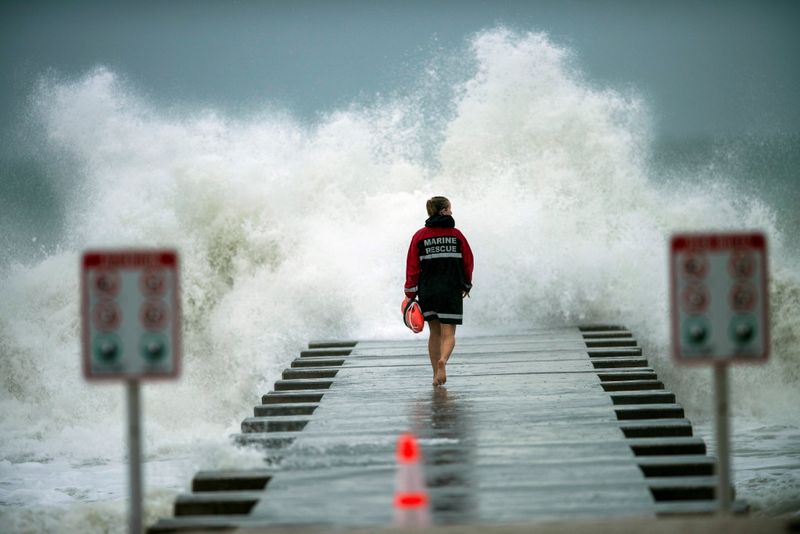 A lifeguard walks to the end of the jetty after
