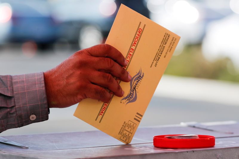 FILE PHOTO: An election worker places a mail-in ballot into