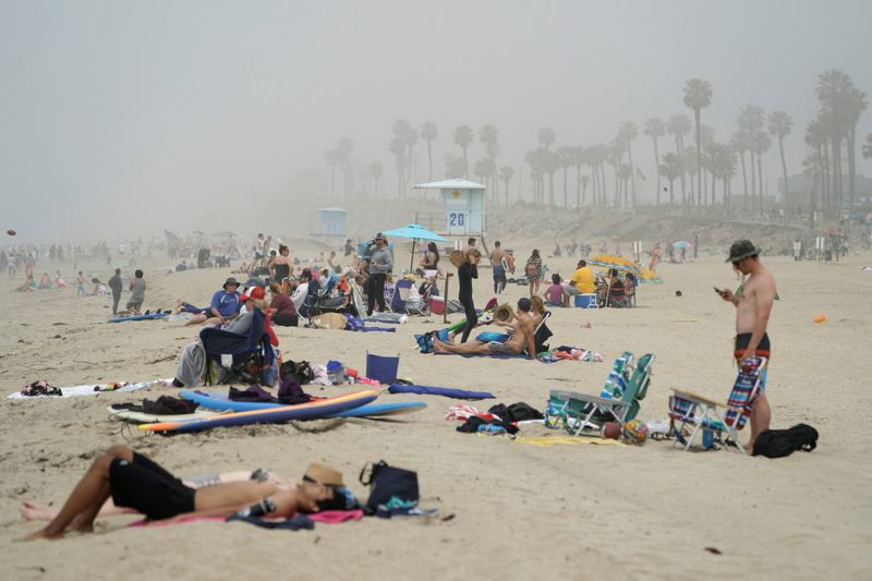 FILE PHOTO: People sit in groups at Huntington City Beach