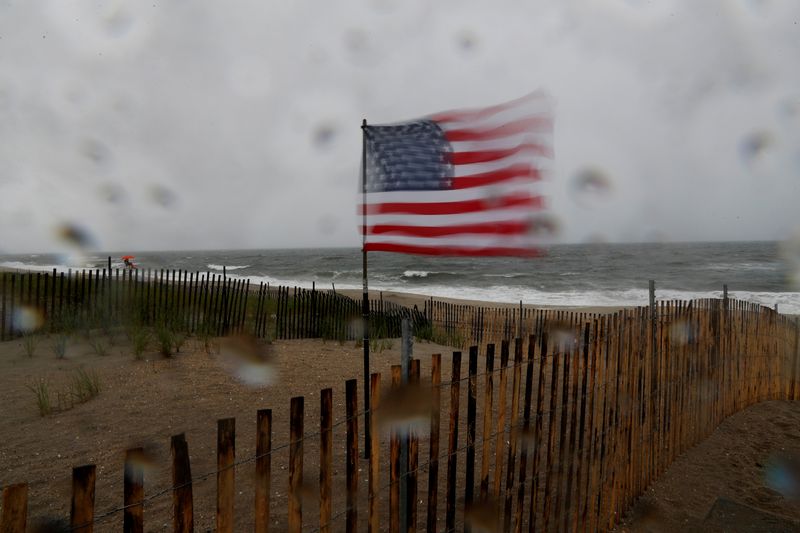 A U.S. flag blows in heavy wind at the beach,