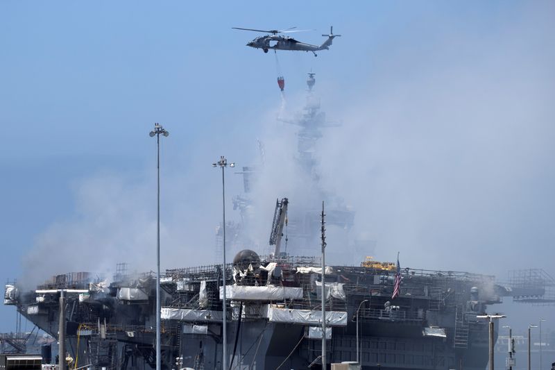 U.S. Navy helicopters continue fighting a fire on the amphibious