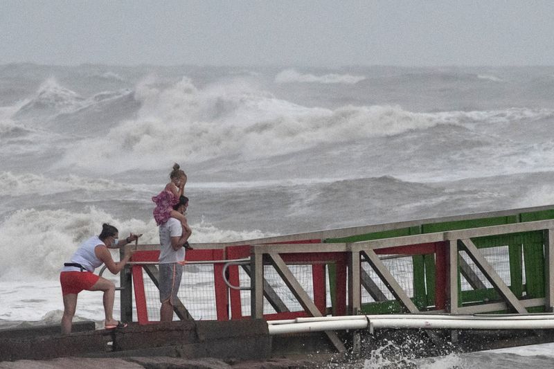 A family watches high swells from Hurricane Hanna from a