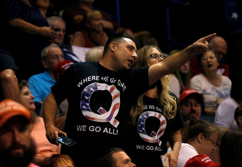 FILE PHOTO: Supporters wearing shirts with the QAnon logo, chat