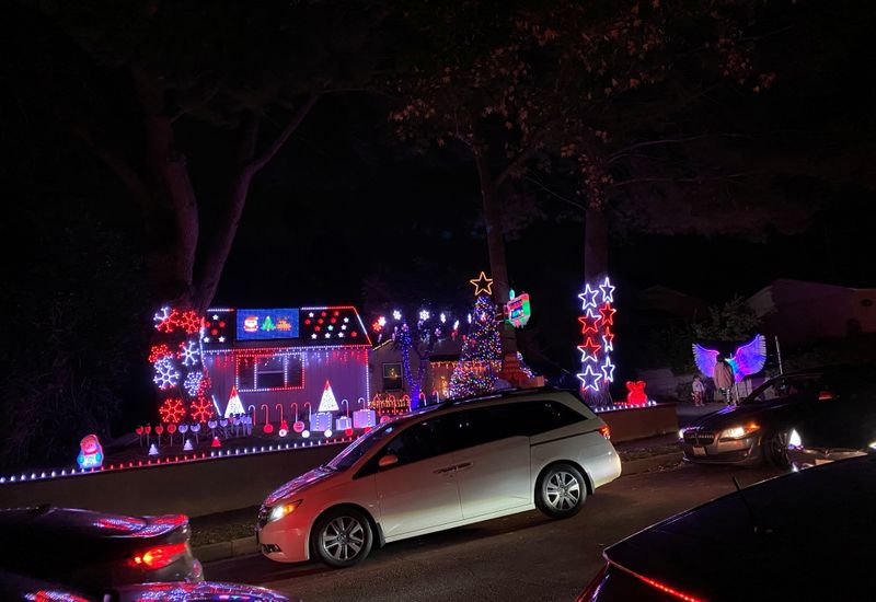 People drive by a house decorated with Christmas lights during