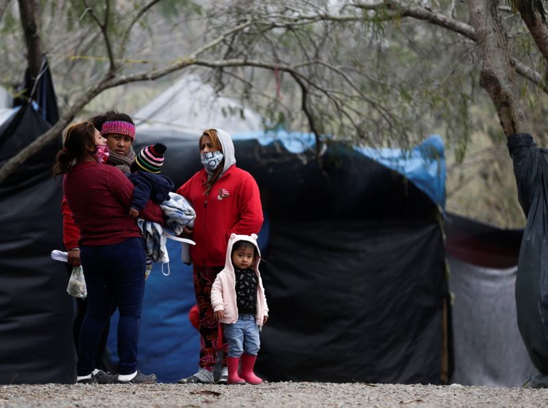 Asylum seekers stand inside a migrant encampment in Matamoros