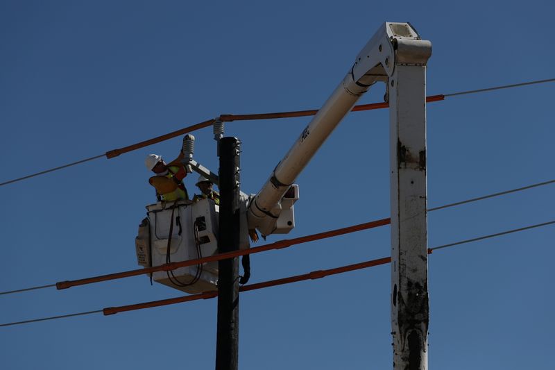 FILE PHOTO: Workers install a utility pole to support power