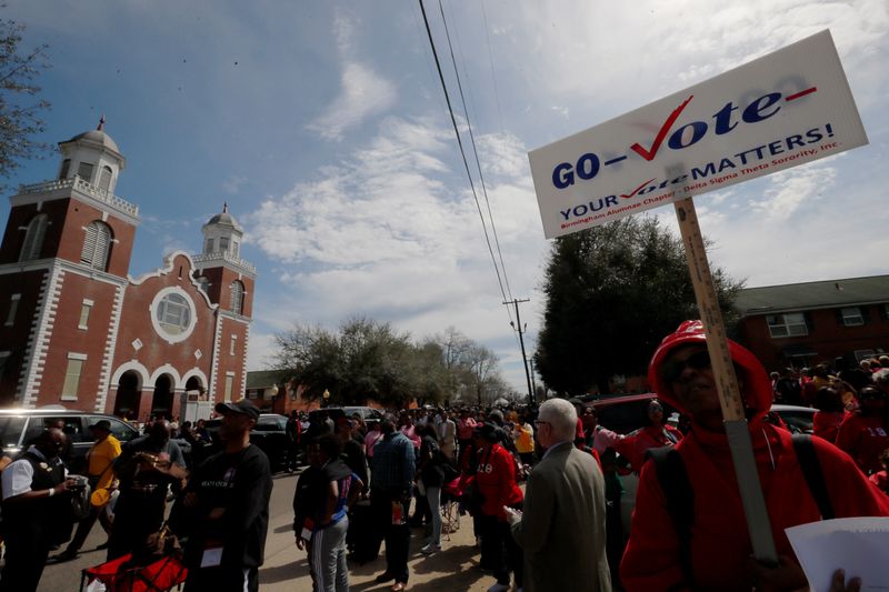 A woman carries a sign reading “Go Vote” in Selma