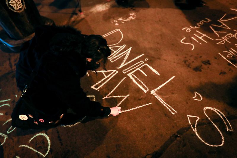 FILE PHOTO: A protester writes on a street with chalk