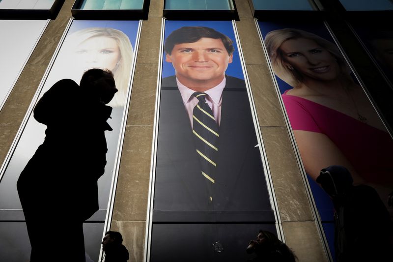 People pass by a promo of Fox News host Tucker
