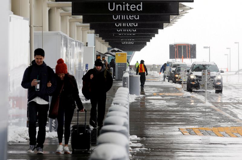 FILE PHOTO: Travelers walk past the United check-in area after