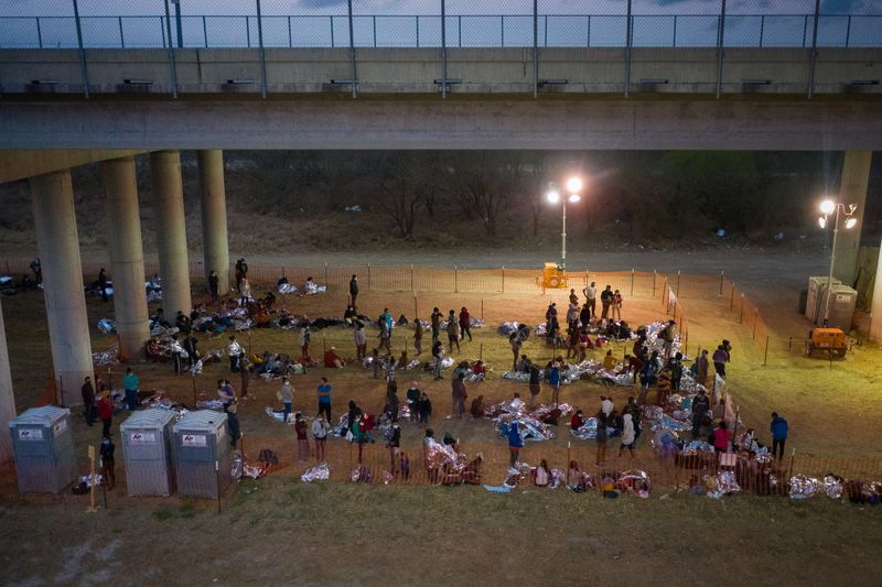 Migrant families and unaccompanied minors take refuge at a processing