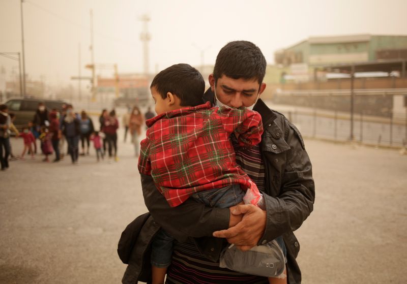 A migrant asylum-seeker from Central America carries his son near