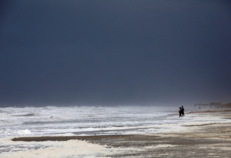 FILE PHOTO: A couple look out at the roiling surf