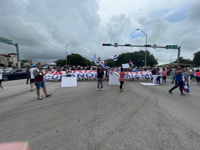 People hold flags, signs and a banner on the Palmetto