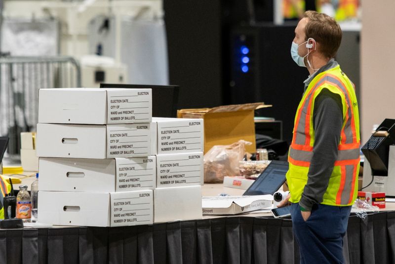 An electoral worker stands next to boxes with ballot material