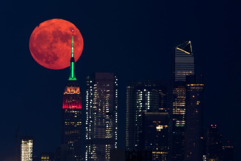 The full moon rises behind the Empire State Building in